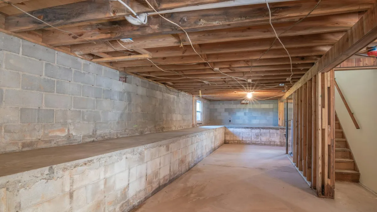 An unfinished residential basement with exposed framing and cinder-block foundation walls.